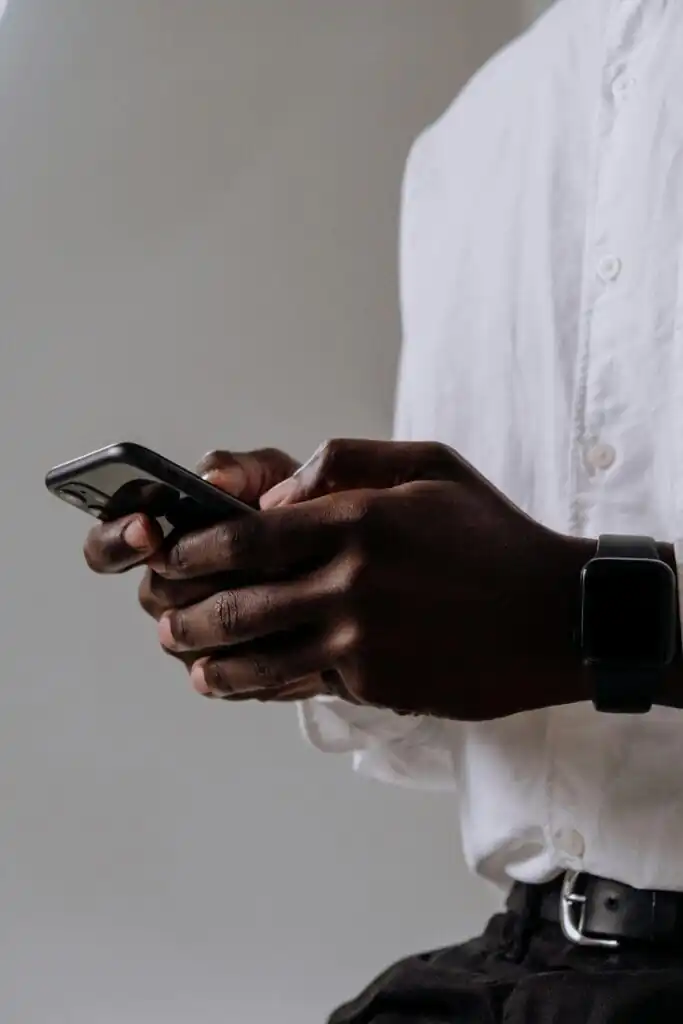 a man wearing white shirt is using iPhone for messaging