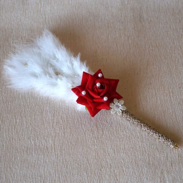 Close-up of a decorative Nikah signing pen featuring a glittery lace-wrapped barrel, a red artificial rose with pearl-studded floral accents, and white feather plumes.
