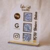 A customizable QR code stand made using imported acrylic and golden sheets is perfect for business desks and exhibitions. The QR codes and brand name can be customized. The stand is removable, and the size of the product is 5 by 7 inches.