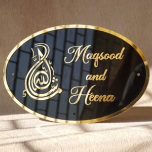 Black oval acrylic nameplate with gold Arabic calligraphy, featuring a small dangling gold heart plate embossed with the child’s name—a personalized, elegant keepsake for your home.