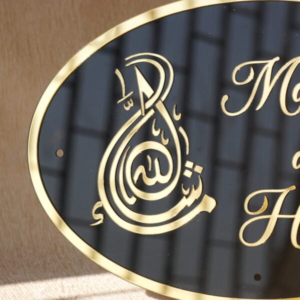 Black oval acrylic nameplate with gold Arabic calligraphy, featuring a small dangling gold heart plate embossed with the child’s name—a personalized, elegant keepsake for your home.