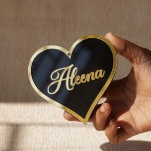 Black oval acrylic nameplate with gold Arabic calligraphy, featuring a small dangling gold heart plate embossed with the child’s name—a personalized, elegant keepsake for your home.