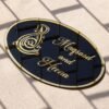 Black oval acrylic nameplate with gold Arabic calligraphy, featuring a small dangling gold heart plate embossed with the child’s name—a personalized, elegant keepsake for your home.