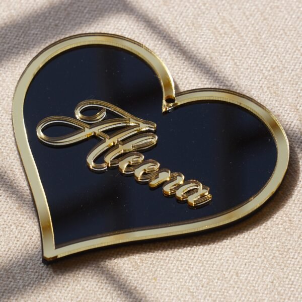 Black oval acrylic nameplate with gold Arabic calligraphy, featuring a small dangling gold heart plate embossed with the child’s name—a personalized, elegant keepsake for your home.
