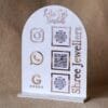 Personalized dome-shaped QR code scanner stand made using rose gold and white acrylic sheet with 3 QR code options and personalized brand name written on the side.