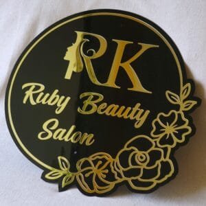 Custom beauty salon sign in black and gold acrylic with a floral design, shown on a white background.