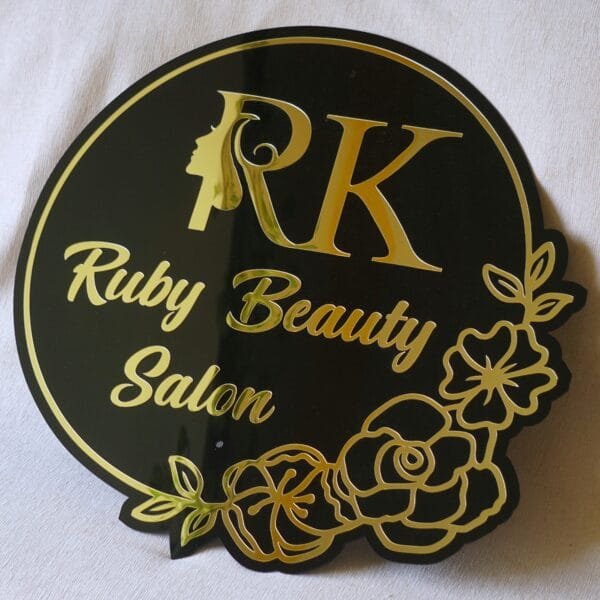 1000014739 Custom beauty salon sign in black and gold acrylic with a floral design, shown on a white background.
