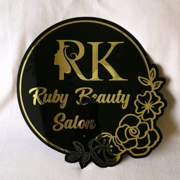 Elegant black acrylic shop sign with custom 3D gold lettering and a decorative floral border.