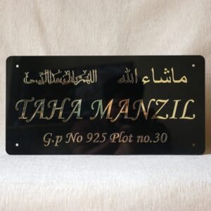 Front view of a personalized 'TAHA MANZIL' Islamic name plate in black acrylic with gold Arabic calligraphy reading 'MashaAllah'.