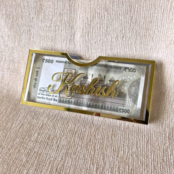 20250720_125152 Angled view of a personalized Rakhi money envelope with the name 'Kashish' in 3D gold acrylic script, highlighting its premium quality and custom feel.