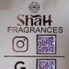 Close-up of the custom logo and 'Shah Fragrances' brand name on a rose gold acrylic QR display, with the Instagram logo and QR code below.