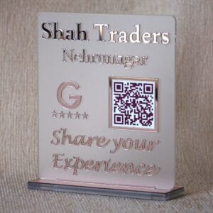 Angled view of the rose gold 'Shah Traders' Google Review QR code sign, showing the depth of the glass-like lettering and stable base.
