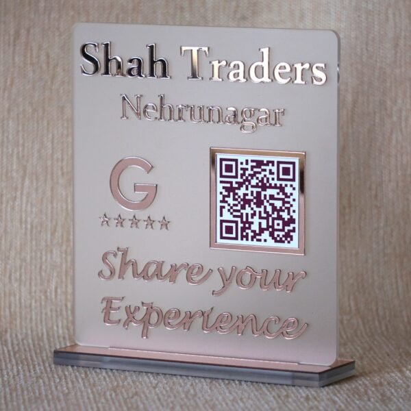 Angled view of the rose gold 'Shah Traders' Google Review QR code sign, showing the depth of the glass-like lettering and stable base.