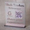 Angled view of the rose gold 'Shah Traders' Google Review QR code sign, showing the depth of the glass-like lettering and stable base.