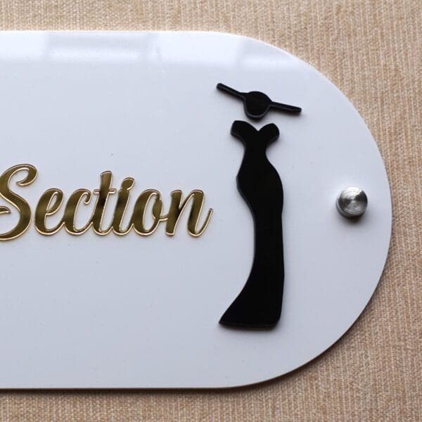 Close-up view of the black female silhouette icon in a gown and a silver mounting stud on the 'Female Section' wall sign.