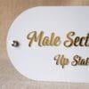 Detailed close-up of the elegant gold script text on the 'Male Section' wayfinding signage for a retail store.