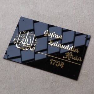 Side-angle perspective of a personalised Masha'Allah nameplate, showcasing the reflection on the sleek black acrylic surface and the raised golden calligraphy.