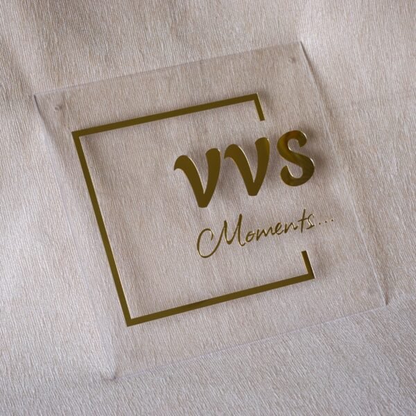 A 12x12 inch clear acrylic office sign with raised gold lettering, showing the pre-drilled mounting hole in the corner.