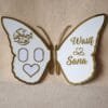 Full view of an open white and gold butterfly nikah thumb board, customized with names 'Wasif & Sana' on one wing and Arabic calligraphy with photo slots on the other.