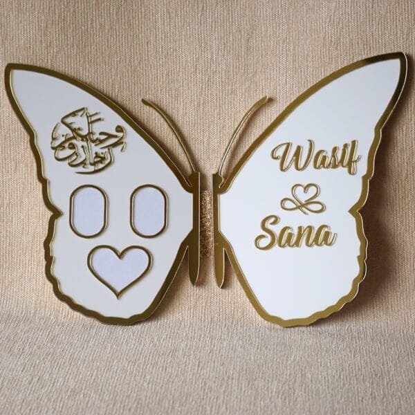 DSC08320 Full view of an open white and gold butterfly nikah thumb board, customized with names 'Wasif & Sana' on one wing and Arabic calligraphy with photo slots on the other.