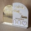 A clear, front-facing view of the personalised Nikah thumb board for 'Wasif & Sana', highlighting the shiny gold acrylic lettering and date against the white plaque.