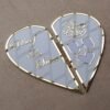 The open heart-shaped Nikah board under cool lighting, giving the white acrylic a modern, greyish tint and highlighting the reflective gold.