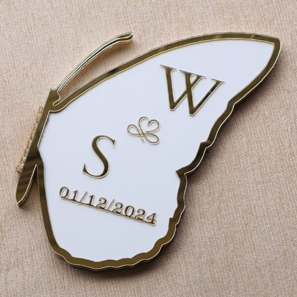DSC08357 Angled view of a folded acrylic nikah board shaped like a butterfly wing, personalized with initials 'W & S' and date '01/12/2024'.