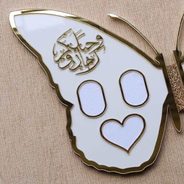 DSC08359 Close-up of the folded butterfly nikah board wing featuring golden Arabic calligraphy 'And We Created You In Pairs' and three photo frames (two oval, one heart).