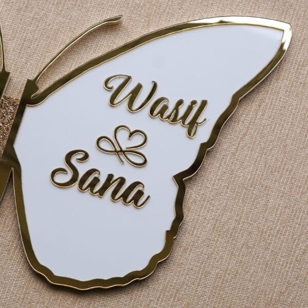 DSC08360 Close-up on the right wing of a butterfly nikah board, showcasing the elegant custom names 'Wasif & Sana' in golden script on a white background.
