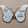 A personalized butterfly-shaped nikah keepsake board in white and gold, open to display the names 'Wasif & Sana' and Arabic calligraphy.