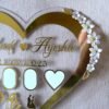 Close-up on the right side of the heart-shaped wedding keepsake, showing the delicate white and gold floral embellishments.