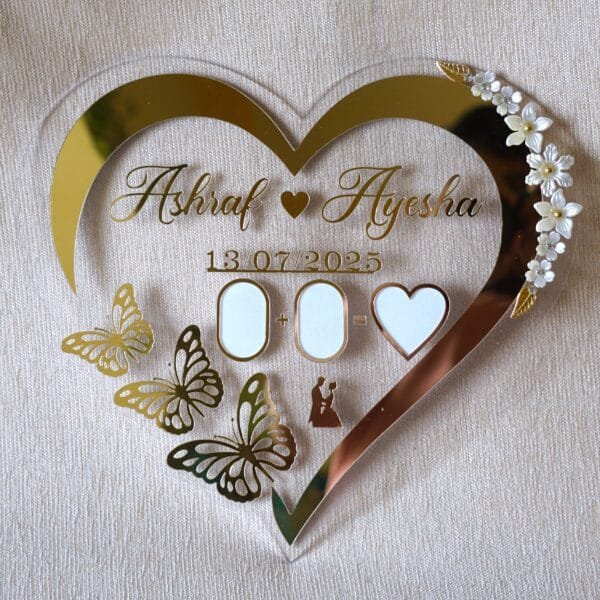 1751816649503 Full front view of a heart-shaped acrylic Nikah thumb board, personalized with the names 'Ashraf & Ayesha' and a date.