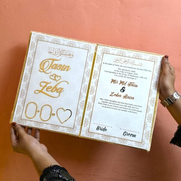 20250721_135649 A person holding the open Islamic wedding booklet, showcasing the beautiful internal design and gold foil text against a white background.