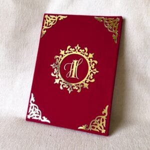 Angled view of the elegant red and gold custom Nikah Nama certificate cover, highlighting the shiny 3D acrylic 'IH' monogram.