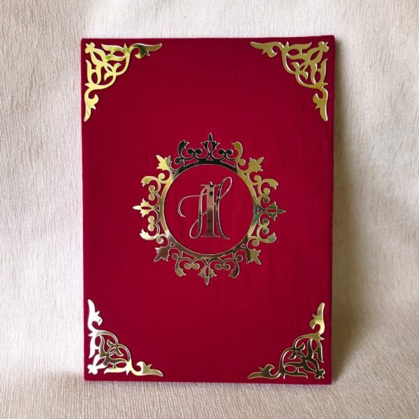 Closed red velvet-textured Nikah Nama booklet with a custom gold acrylic monogram 'IH' in an ornate central design.