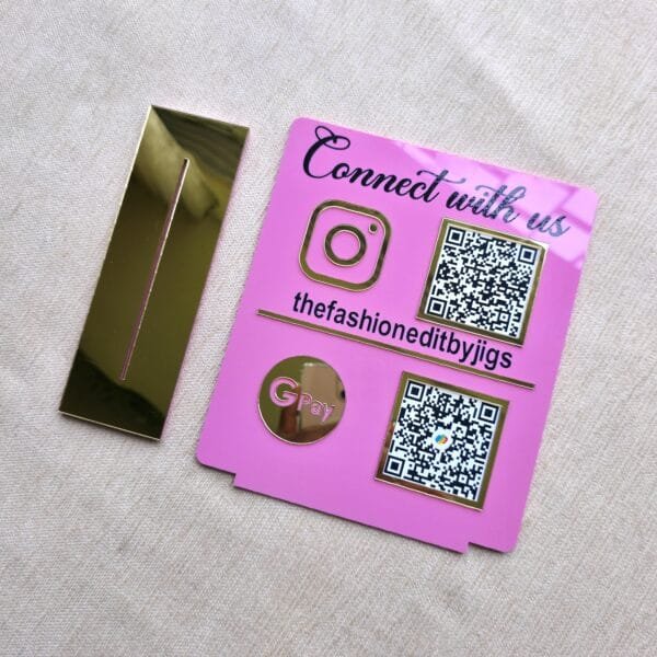 The two separate pieces of the QR code stand laid flat: the pink engraved plaque and the reflective gold base, showing the product before assembly.