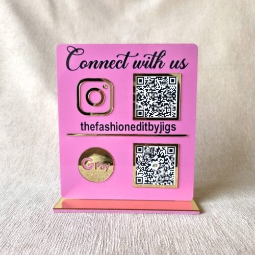 Front view of the assembled pink and gold acrylic QR code stand showing Instagram and GPay codes, customized for 'thefashioneditbyjigs'.