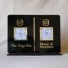 Front-facing view of a custom dual QR code display stand in black and gold acrylic, featuring Instagram links for 'The Yoga Plus' and 'House of Nutrition'.