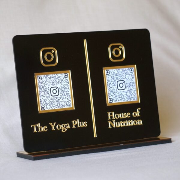 Close-up of an elegant black acrylic stand with 3D gold lettering and two customizable Instagram QR codes for business marketing.