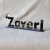 Side-angle view of the 'Zaveri' custom acrylic nameplate with a gold crown, highlighting its 3D effect.