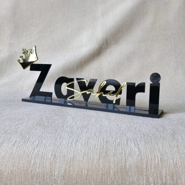 Side-angle view of the 'Zaveri' custom acrylic nameplate with a gold crown, highlighting its 3D effect.