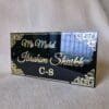 Angled view of the black and gold acrylic nameplate showing the glossy, reflective surface and 3D embossed text.