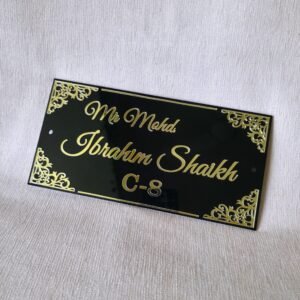 Close-up shot of the elegant black acrylic door sign with custom golden lettering, highlighting the intricate corner details.