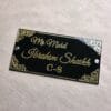 Top-down view of the custom acrylic nameplate on a textured beige surface, showcasing the full design and layout.