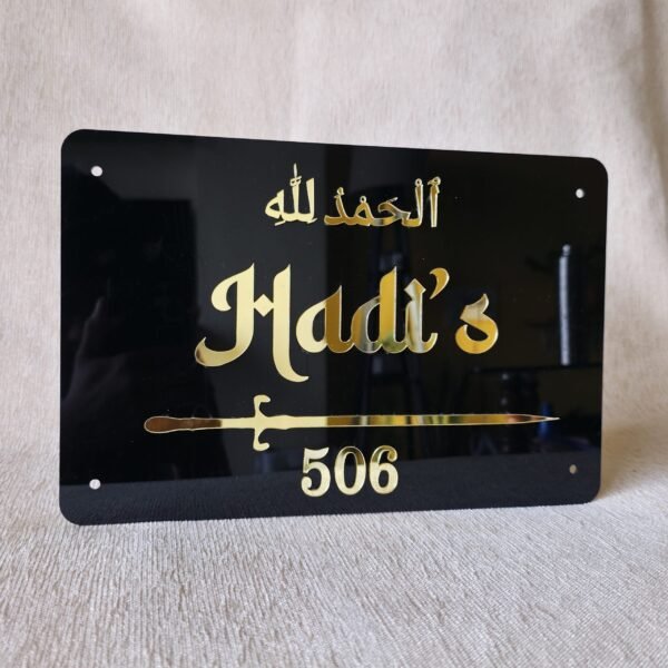 Custom black acrylic Islamic nameplate with 3D gold lettering for 'Hadi's 506' and 'Alhamdulillah' calligraphy, shown straight on.