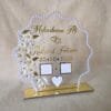Front view of a personalized acrylic Nikah thumb board with a pearl frame, gold lettering, and white floral details, standing upright on its gold base.
