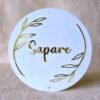 Front-on view of the custom round acrylic name plate in white and gold, showing the pre-drilled holes for mounting.
