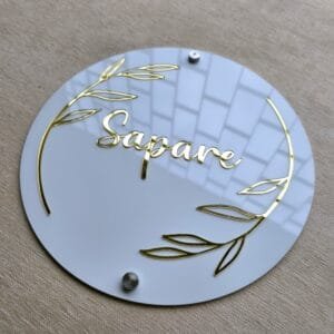 Custom round acrylic name plate for home with silver mounting studs installed, showcasing the 3D floating effect of the sign.