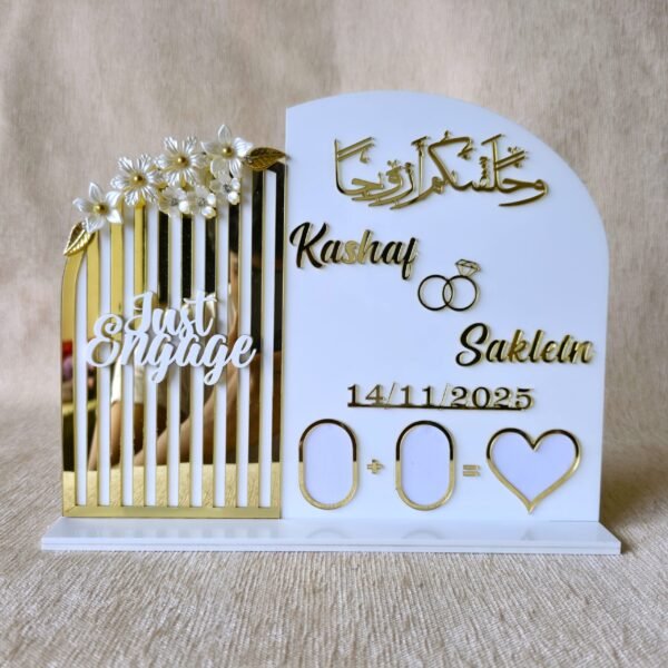 A front-view of a personalised white and gold acrylic engagement thumb board with custom names 'Kashaf' and 'Saklein'.