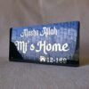 Side angle view of a black acrylic nameplate with 'Masha Allah' in reflective white lettering, showing the sky's reflection.